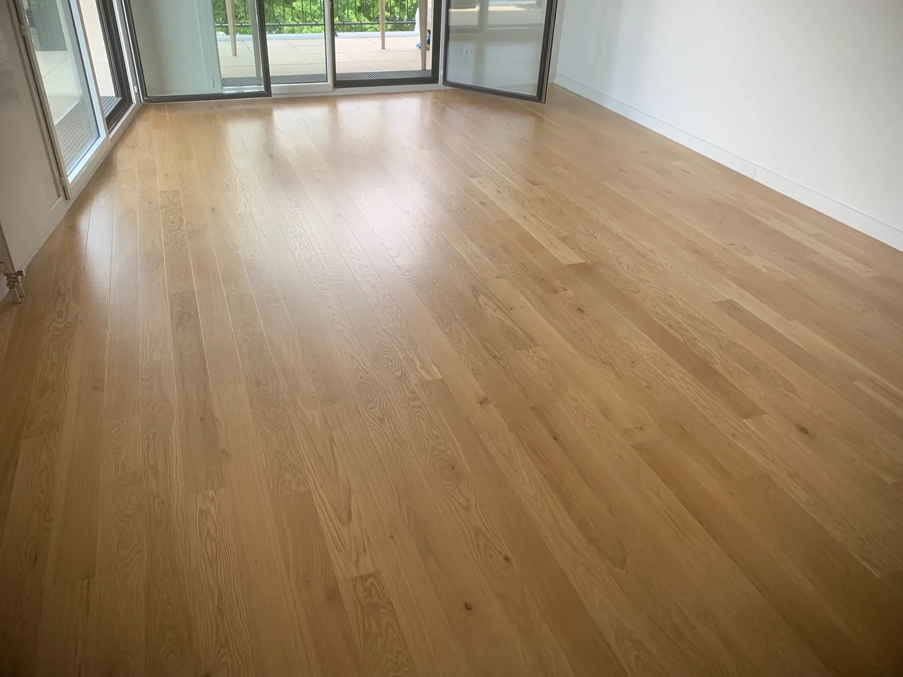 Parquet en lames larges dans une pièce lumineuse ouverte sur une baie vitrée.