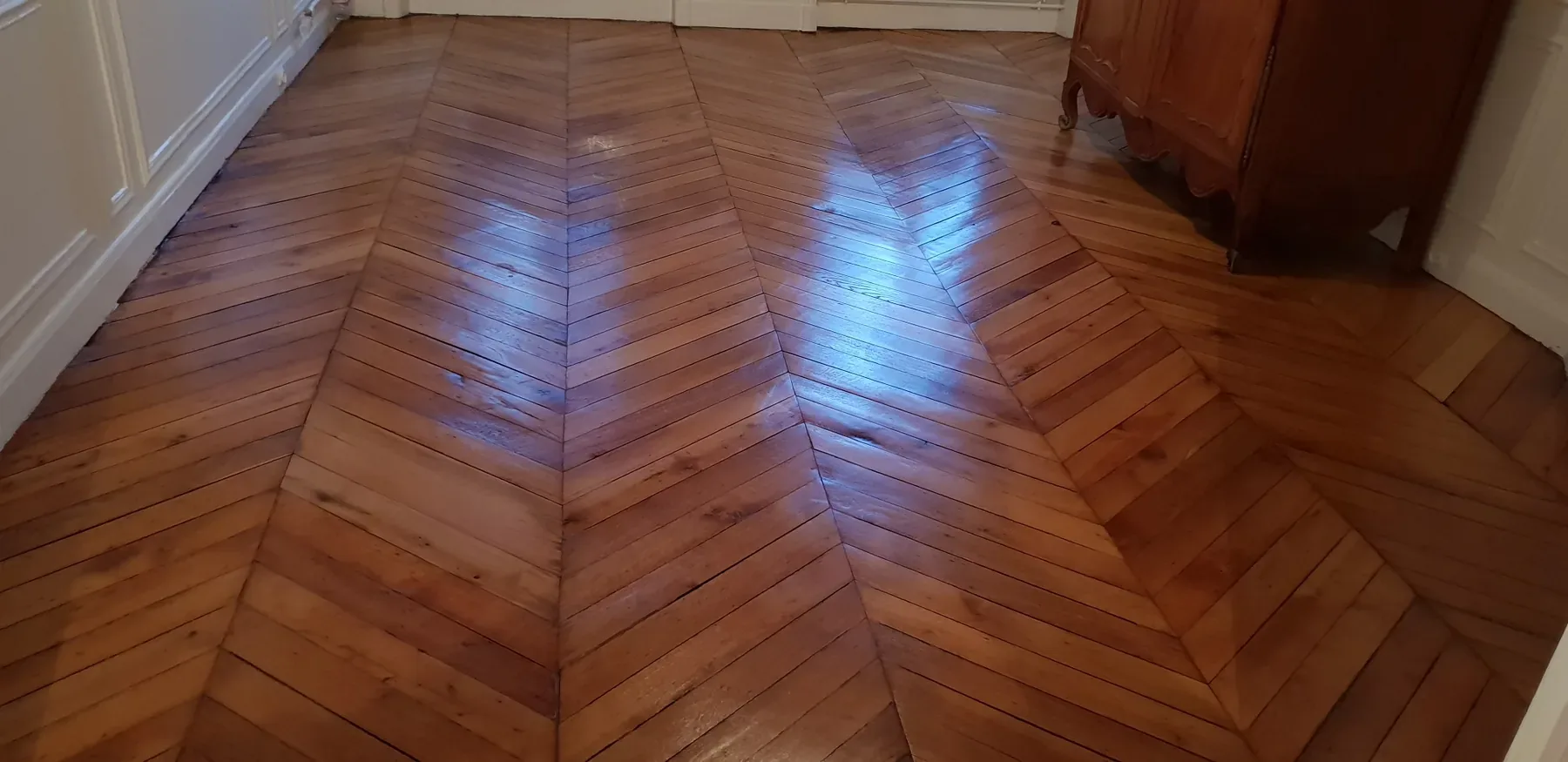Vue d’un parquet en chevrons à la surface brillante, hors paire avant/après.